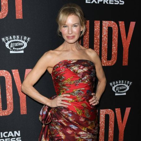 rene standing in a red strapless gown with flower prints, hair up ina bun  